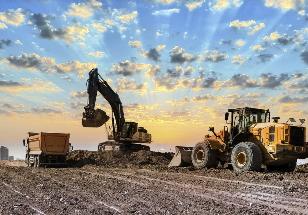 Excavators working on construction site at sunset